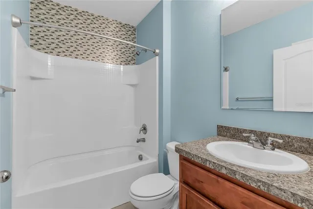 a bathroom with a granite countertop sink a toilet and bathtub