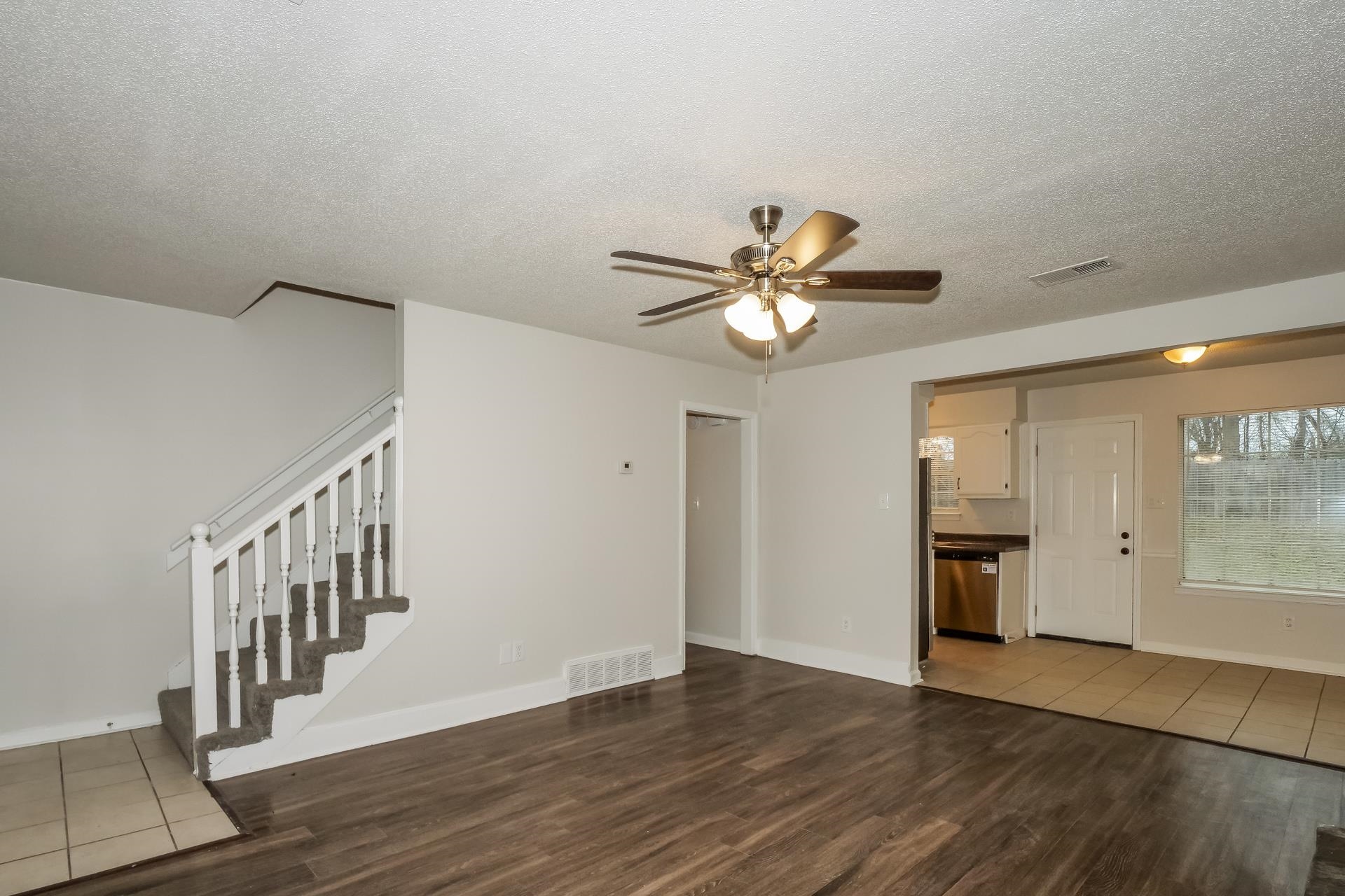 4696 Crestfield Road Millington, TN 38053 - Photo 4 of 17 Unfurnished living room featuring dark wood-style flooring, a textured ceiling, stairs, and a ceiling fan
