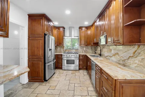 a kitchen with stainless steel appliances granite countertop a stove a sink and a refrigerator