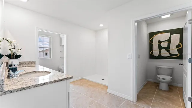 a spacious bathroom with a granite countertop sink and a toilet