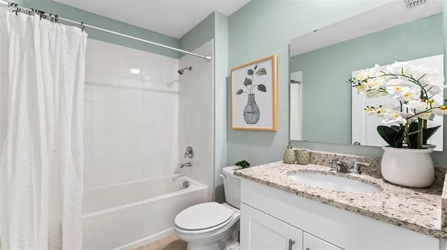 a bathroom with a granite countertop sink a toilet and shower