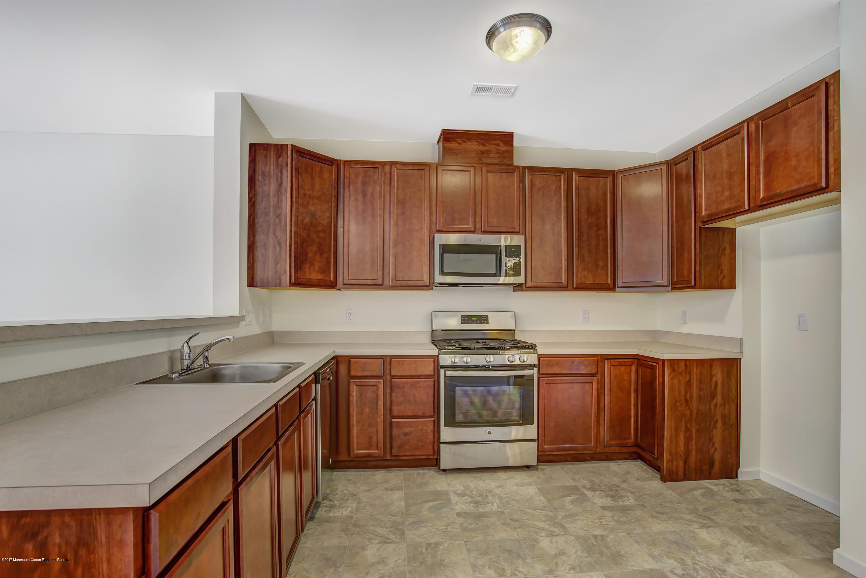 58 Rockingham Way Manchester Township, NJ 08759 - Photo 6 of 18 a kitchen with stainless steel appliances granite countertop a sink stove and cabinets