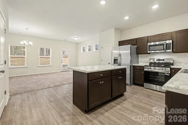 a kitchen with stainless steel appliances kitchen island granite countertop a stove a sink and a refrigerator