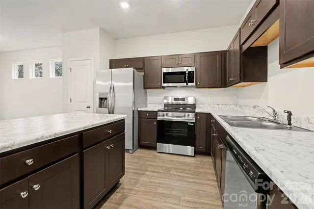 a kitchen with stainless steel appliances granite countertop a sink stove microwave and refrigerator