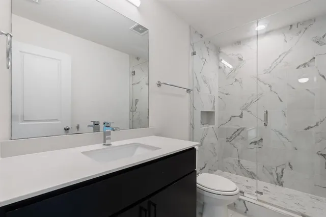 a bathroom with a sink toilet double vanity and shower