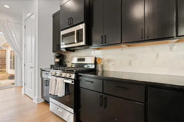 a kitchen with stainless steel appliances granite countertop a stove a microwave and a refrigerator