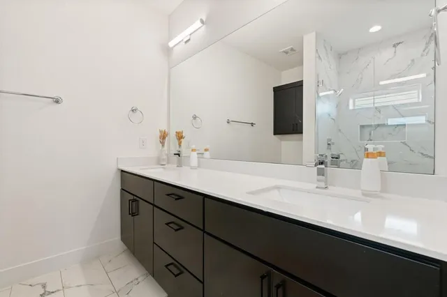 a bathroom with a double vanity sink a mirror and a shower