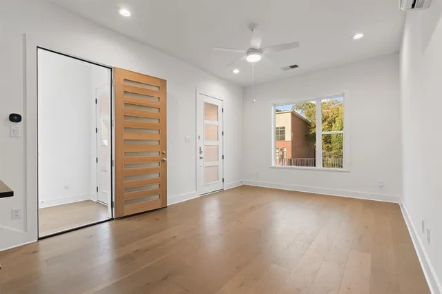 an empty room with wooden floor and windows