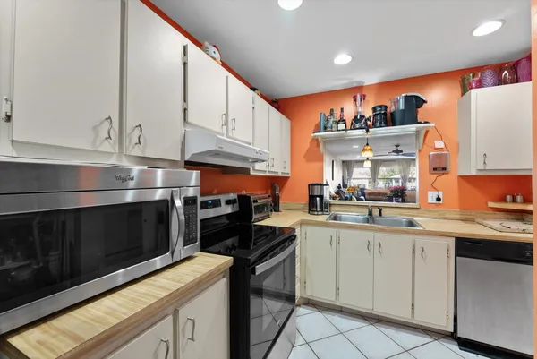a kitchen with stainless steel appliances granite countertop a stove top oven a sink dishwasher and white cabinets
