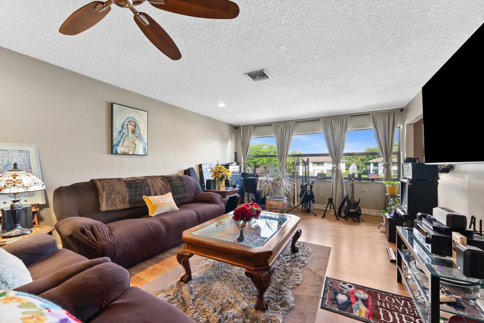3122 Southwest 20th Terrace, Unit 25B2 Delray Beach, FL 33445 - Photo 3 of 32 a living room with furniture a flat screen tv and a table