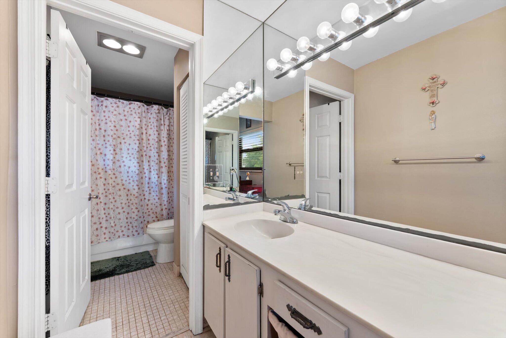 3122 Southwest 20th Terrace, Unit 25B2 Delray Beach, FL 33445 - Photo 9 of 32 a bathroom with a sink a toilet a shower and a mirror