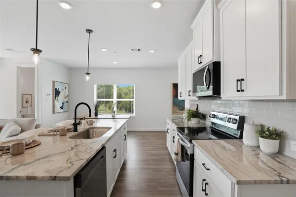 a kitchen with stainless steel appliances granite countertop a sink a stove and a wooden floors