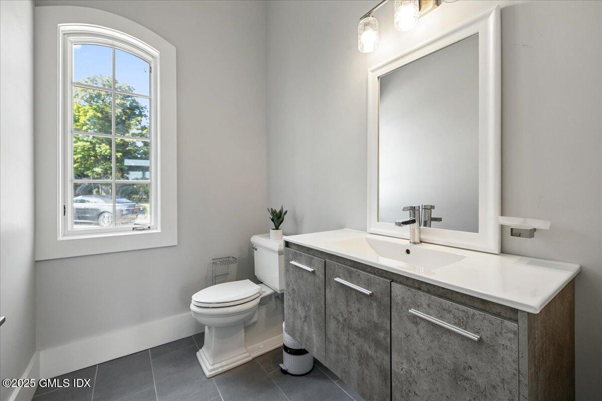 424 Taconic Road Greenwich, CT 06831 - Photo 4 of 35 a bathroom with a toilet a sink a mirror a window and vanity