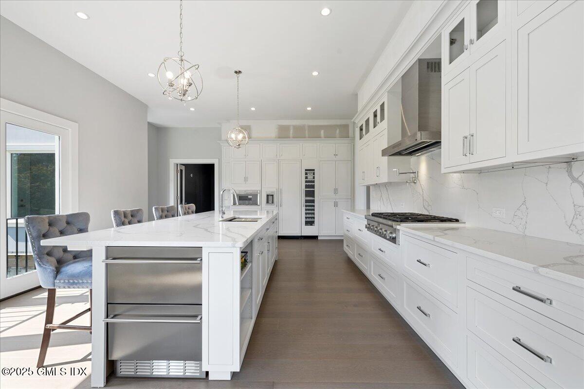 424 Taconic Road Greenwich, CT 06831 - Photo 10 of 35 a large white kitchen with stainless steel appliances granite countertop a stove oven a large island with chairs and refrigerator