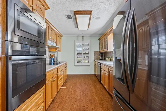 a kitchen with stainless steel appliances granite countertop a refrigerator a stove and a sink with wooden floor