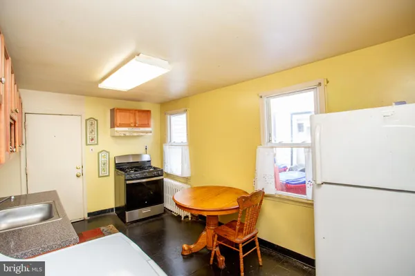 a kitchen with stainless steel appliances a refrigerator a stove a dining table and chairs with wooden floor