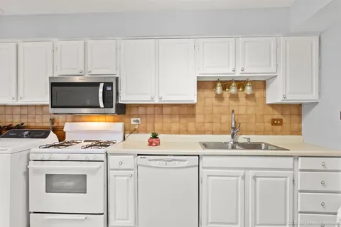 a kitchen with granite countertop white cabinets and white appliances