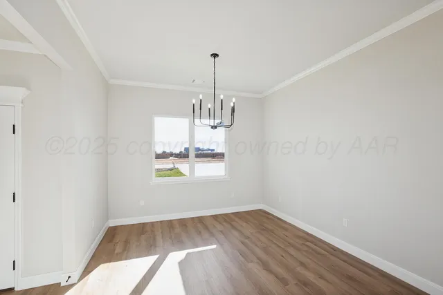 an empty room with wooden floor and chandelier