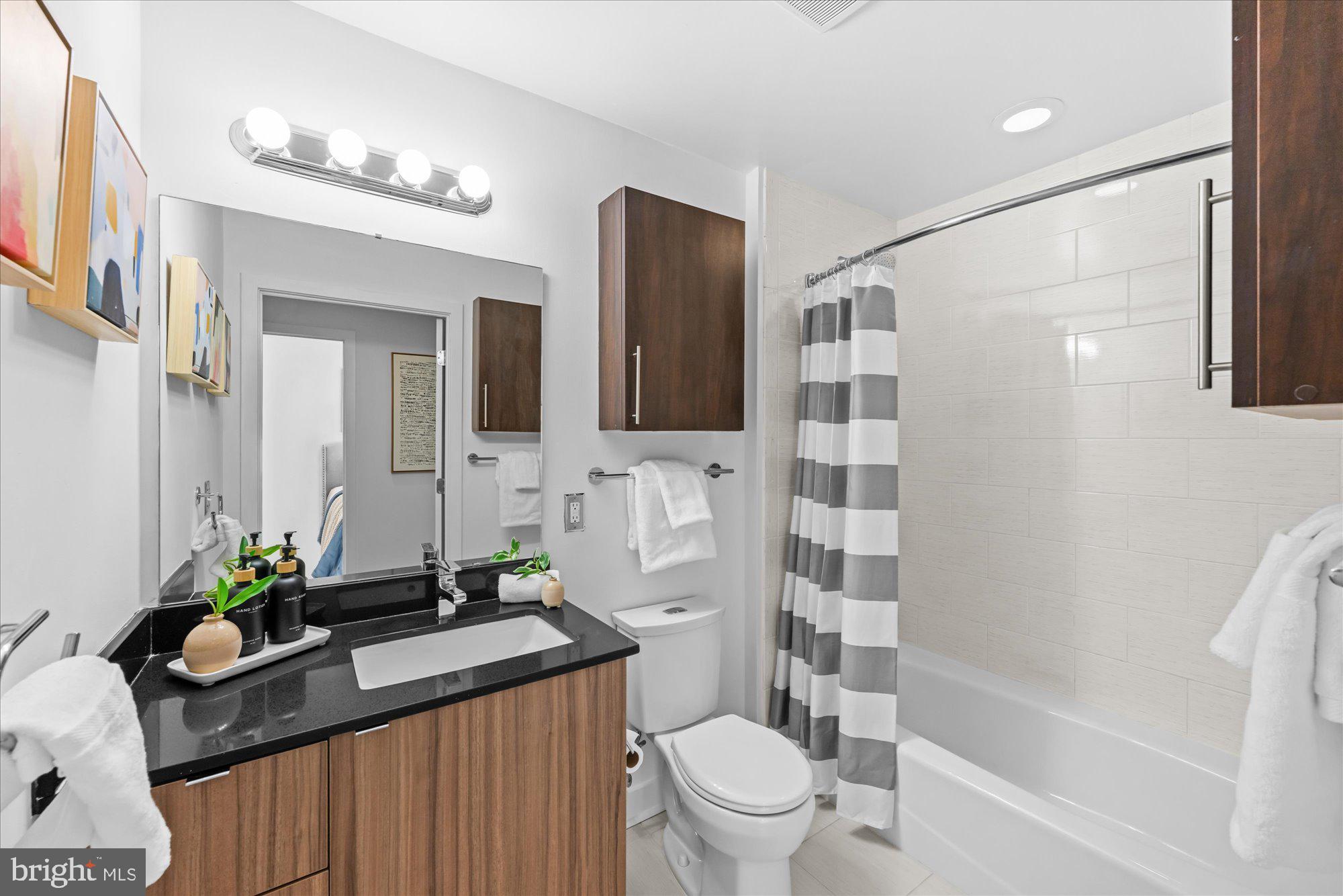 460 New York Avenue Northwest, Unit 504 Washington, DC 20001 - Photo 28 of 62 a bathroom with a granite countertop sink a toilet a mirror a vanity and shower