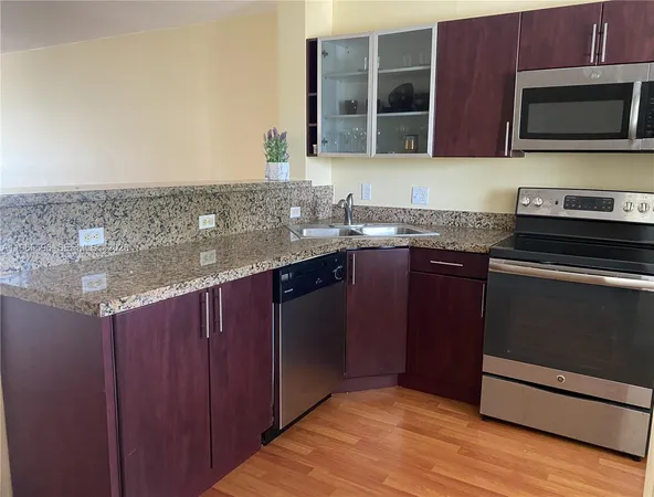 a kitchen with stainless steel appliances granite countertop a refrigerator a sink a stove and wooden floors