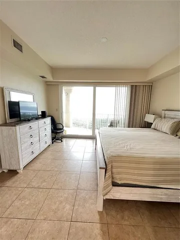a bedroom with a bed and flat tv screen on the dresser