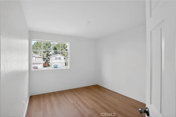 an empty room with wooden floor and window