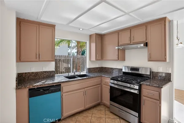 a kitchen with granite countertop stainless steel appliances a stove sink and cabinets