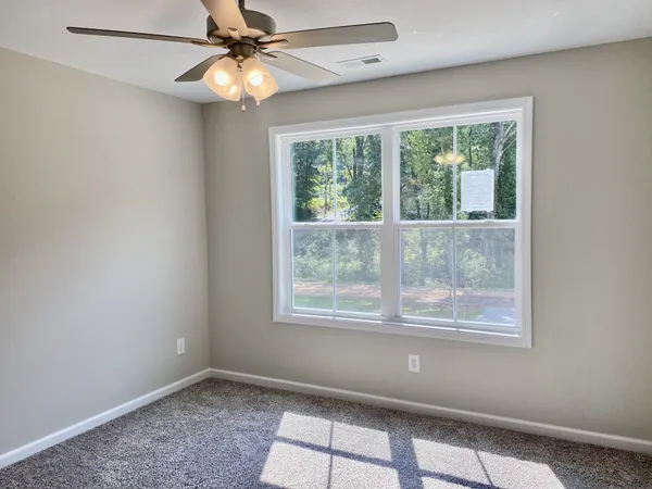 an empty room with a window and a fan