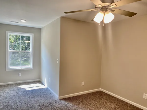 an empty room with a window and a fan