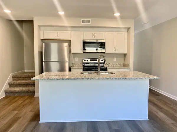 a kitchen with stainless steel appliances a refrigerator a stove a microwave and white cabinets