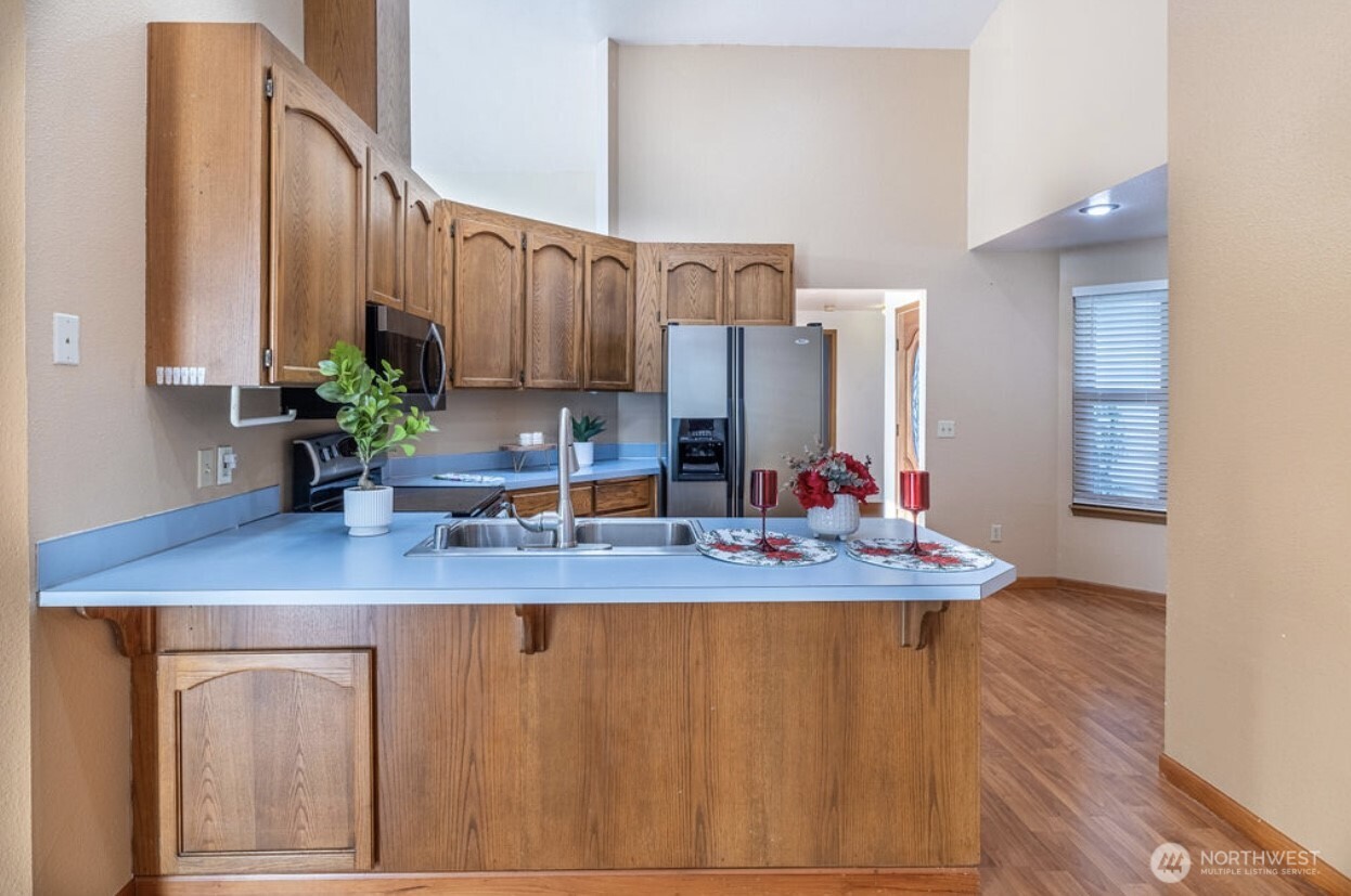 11209 Southeast 267th Place Kent, WA 98030 - Photo 14 of 27 a kitchen with stainless steel appliances granite countertop a sink dishwasher and cabinets with wooden floor