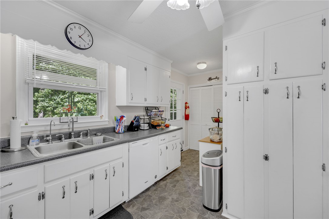 250 Rockcrest Road Cleveland, SC 29635 - Photo 17 of 37 A well-lit kitchen with ample white cabinetry and dual sinks, offering a pleasant view of abundant greenery outside.