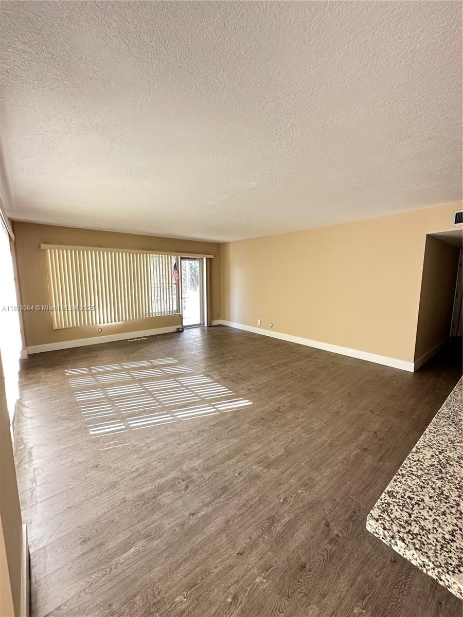 10777 West Sample Road, Unit 301 Coral Springs, FL 33065 - Photo 3 of 12 an empty room with wooden floor and windows