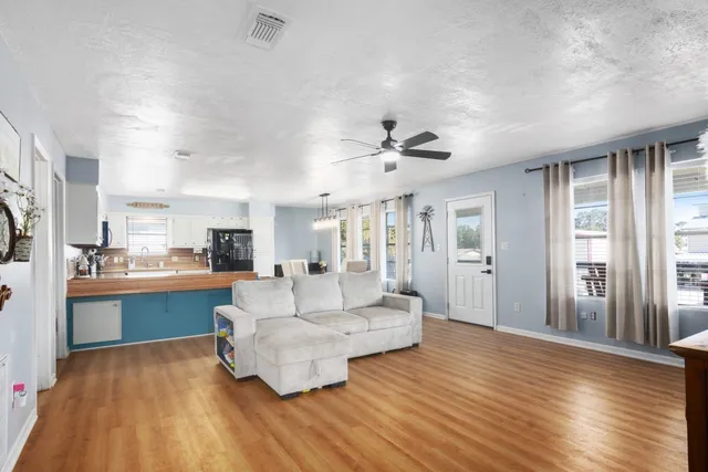 a living room with stainless steel appliances furniture a dining table and a wooden floor