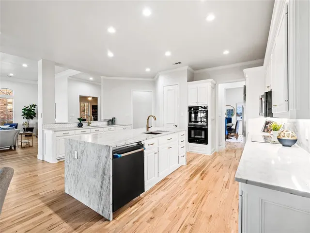 a large kitchen with stainless steel appliances kitchen island granite countertop a large counter top and view of living room