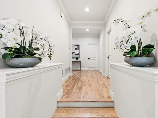 a view of a hallway with wooden floor and a potted plant