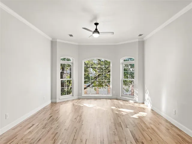 an empty room with wooden floor fan and windows