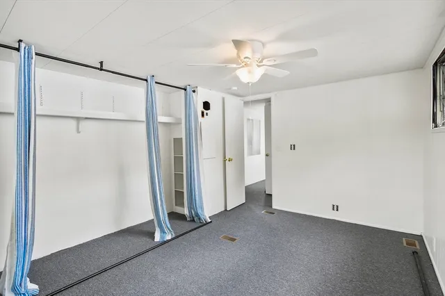 an empty room with a window and a ceiling fan