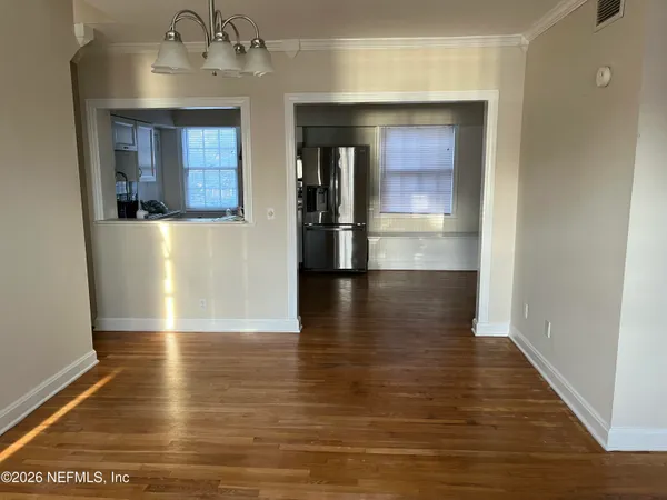 a view of a hallway with wooden floor and a living room