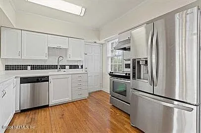 a kitchen with granite countertop a refrigerator sink and stainless steel appliances