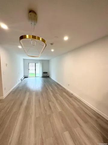 a view of empty room with wooden floor chandelier and entryway