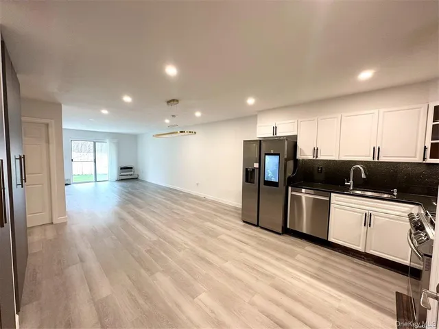 a kitchen with stainless steel appliances kitchen island granite countertop a refrigerator and a sink