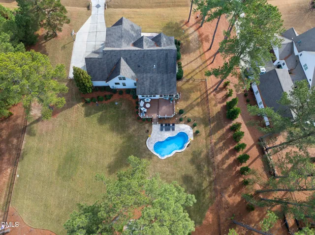 an aerial view of a house with swimming pool and large trees