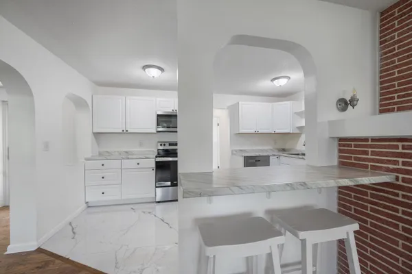 a view of a refrigerator in kitchen and an empty room