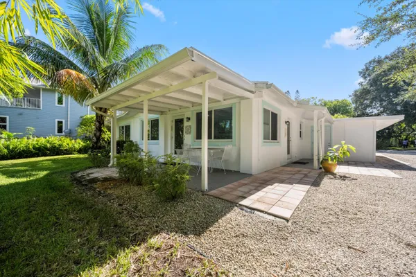 a palm tree sitting in front of a house with a big yard