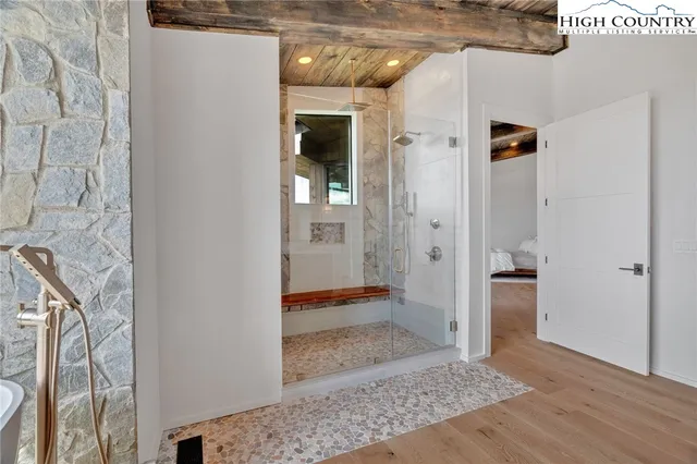 a view of a hallway with wooden floor and a bathroom