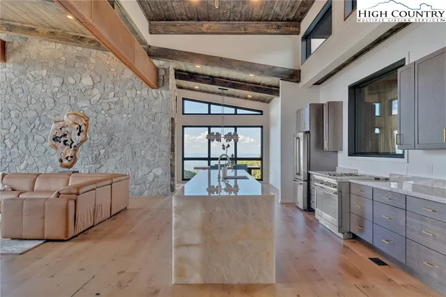 a living room with stainless steel appliances granite countertop furniture and a wooden floor