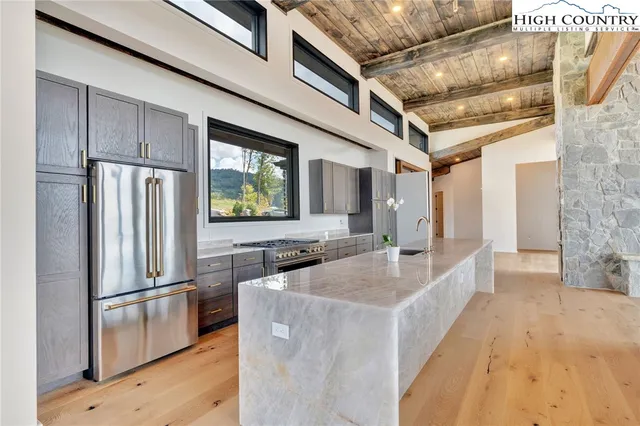 a kitchen with stainless steel appliances granite countertop a refrigerator a stove and a sink with wooden floor