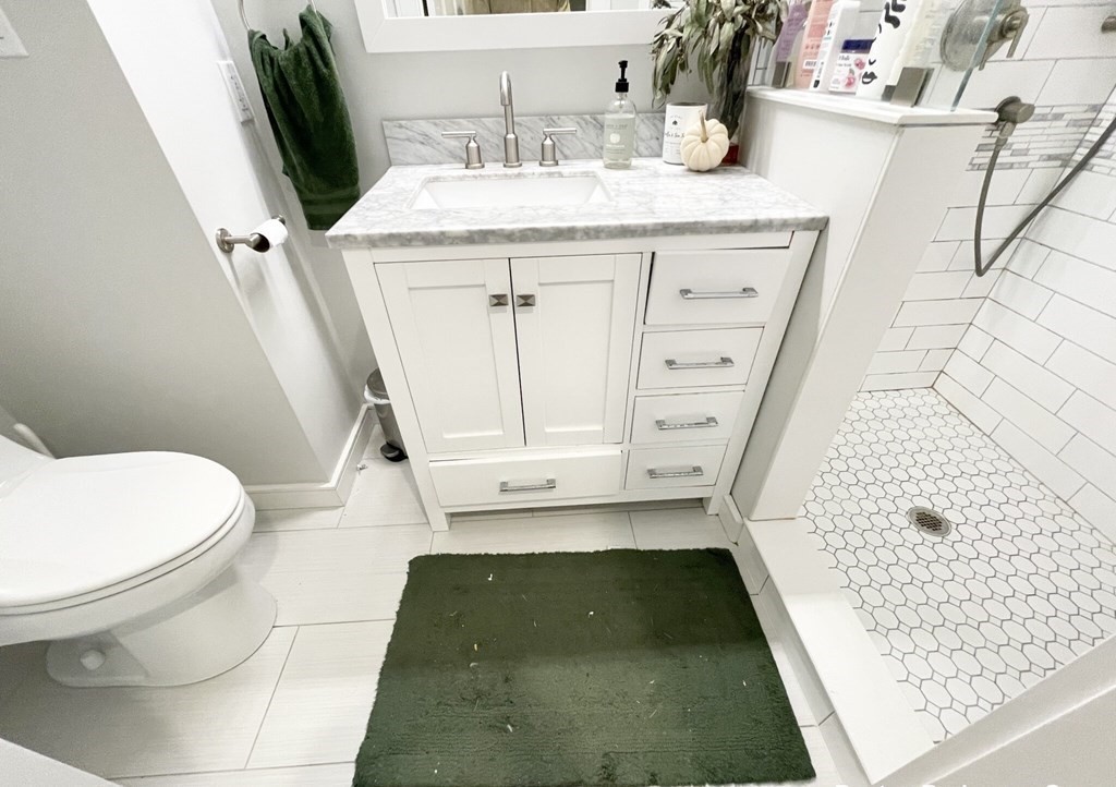 108 Buttonwood Street, Unit 1 Boston, MA 02125 - Photo 11 of 12 a bathroom with a granite countertop sink a toilet a mirror and vanity