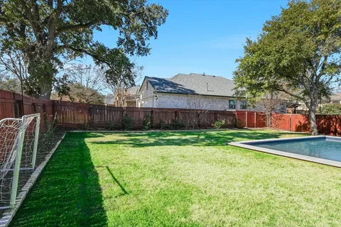 a view of a backyard with table and chairs plants and tree
